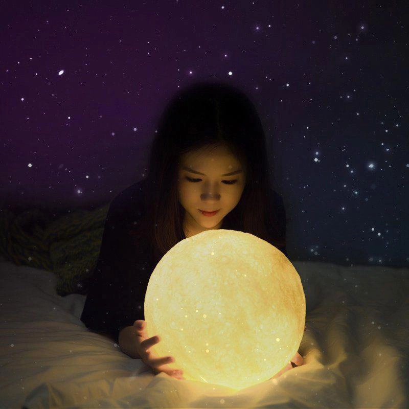 Lampe LED en forme de lune multicolore. Bonne qualité, et à la mose sur un lit avec une petite fille dans une maison.
