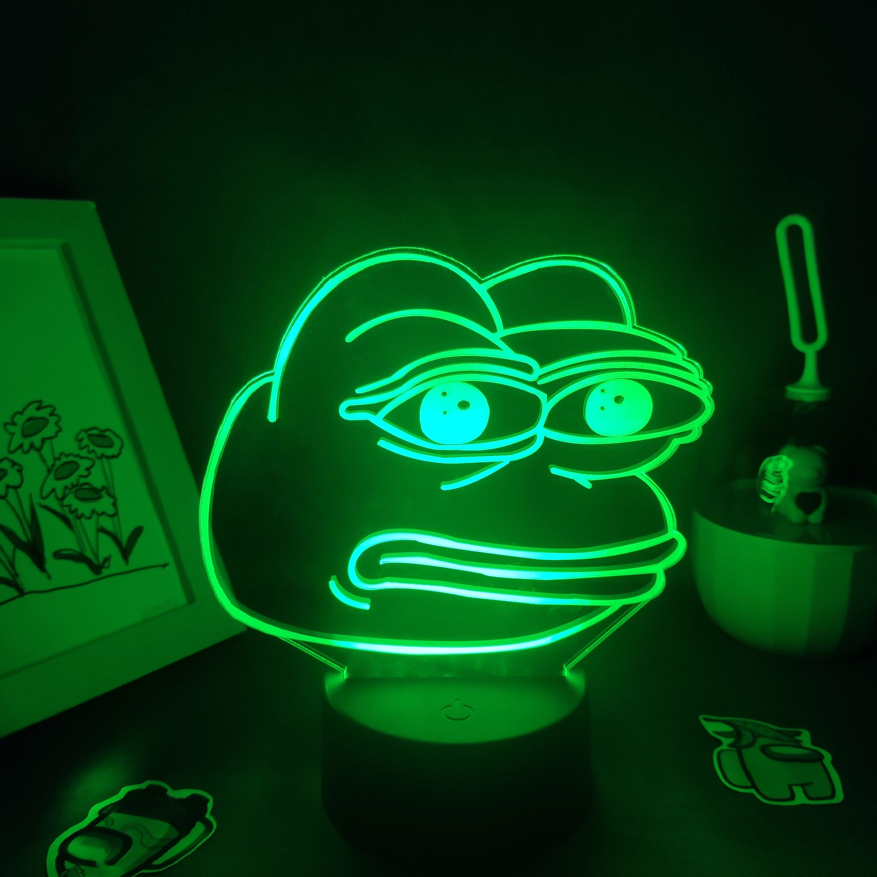 Lampe LED néon grenouille. Bonne qualité et à la mode sur une table à côté d'une cadre photos dans une maison