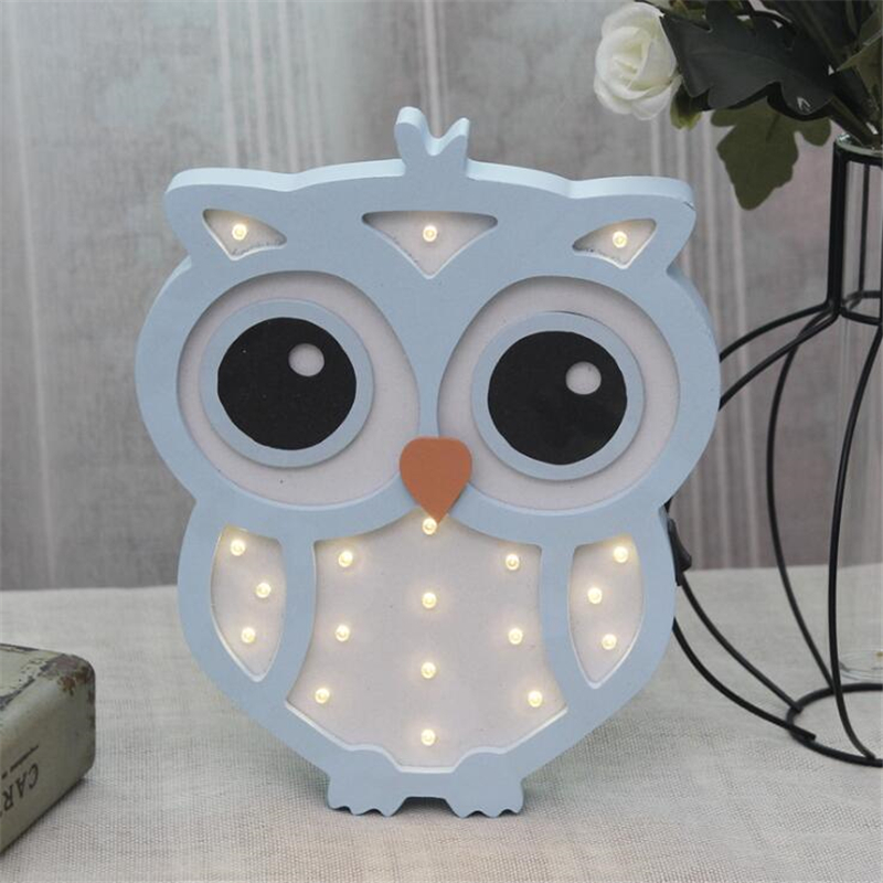 Veilleuse hibou en bois avec lumière LED. Bonne qualité, à la mode. De couleur bleue et blanc sur une table dans une maison