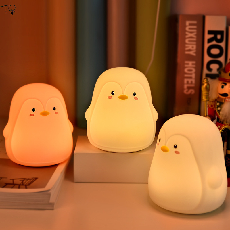 Veilleuse pingouin avec batterie rechargeable. Bonne qualité et à la mode au-dessus des livres avec plusieurs couleurs différentes dans une maison