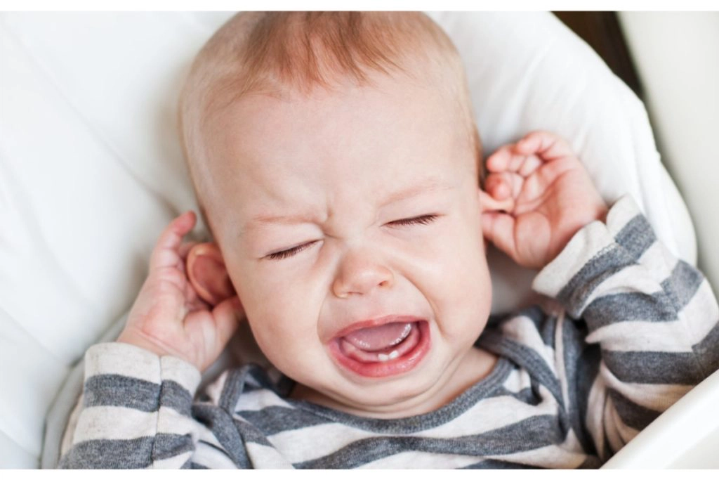 un enfant hurle en fermant les yeux et se touchant les oreilles.