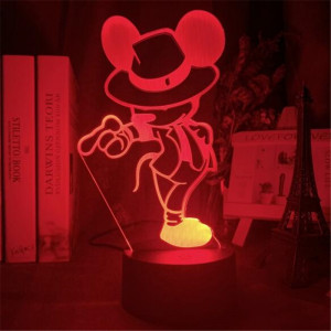 Veilleuse de mickey avec un chapeau qui lui vient sur les yeux et une canne dans sa main droite , la lumière est rouge, la lampe se trouve sur un bureau avec des bibelots à droite et des livres à gauche