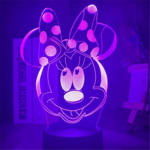 Veilleuse de tête de Minnie rose avec un gros nœud sur sa tête, la lumière est rose, la lampe se trouve sur un bureau avec des bibelots à droite et des livres à gauche