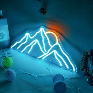 Veilleuse en forme de montagne à led bleu et avec soleil orange posé sur un bureau avec une guirlande à boule multicolore éteinte