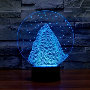 Veilleuse coloré en bleu en forme de montagne avec flocon de neige devant un mur à imitation pierre