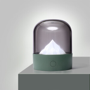 Veilleuse décorative de montagne posé sur un bureau gris et devant un mur blanc