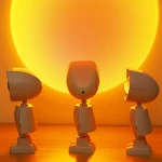 Trois veilleuses à projection astronaute entrain de projeter un coucher de soleil sur le mur, sur fond orange.