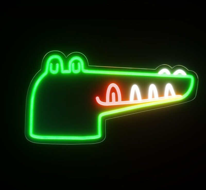 Une veilleuse crocodile en néon vert, jaune et rouge. Sur fond noir