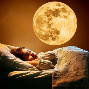 enfant qui dort dans son lit avec une projection de la lune sur le mur à côté de lui faite avec un projecteur LED