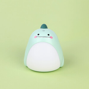 veilleuse dinosaure, deux vertes et deux roses posées sur un bureau et sur des livres