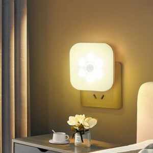 Veilleuse prise à LED avec capteur de mouvement, de couleur blanc chaud au-dessus d'une table de chevet