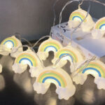 Guirlande lumineuse enfant à motifs d'arc-en-ciel, posée sur une table et un livre blanc