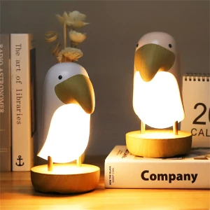 Veilleuse de nuit décorative en forme d'oiseau, posée sur un bureau avec des livres blancs