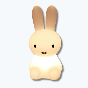 Veilleuse lapin assis en PVC blanc allumée avec deux yeux noirs et une bouche en forme de croix. Sur fond bleu clair.