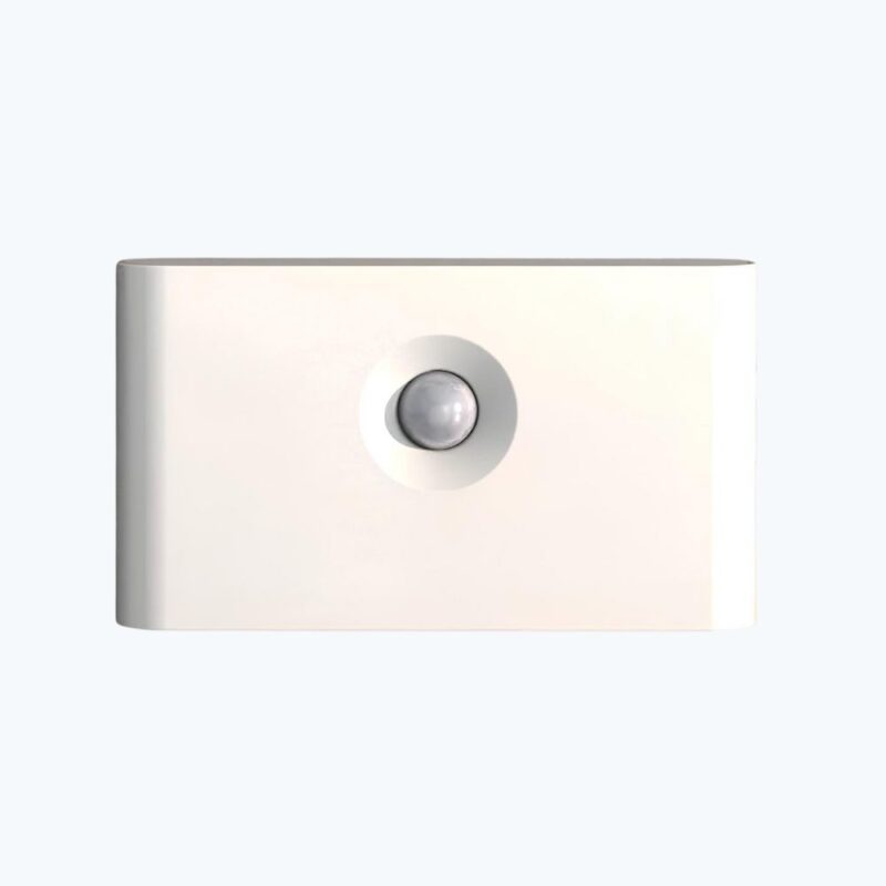 Veilleuse blanche de forme rectangulaire avec rond gris au centre. Sur fond bleu ciel.