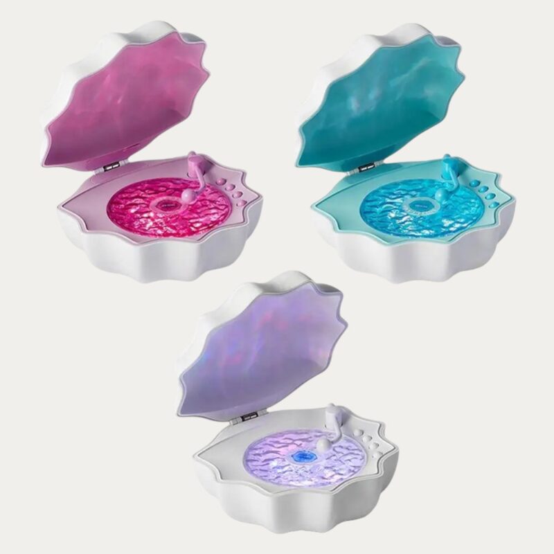 Veilleuse nomade Bluetooth en forme de coquillage entre ouvert laissant entrevoir l'intérieur lumineux, décliné en trois colorie, lavande, rose et bleu ciel sur fond uni gris clair.