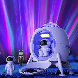 Veilleuse astronaute en forme de vaisseau spatial et projection de galaxie avec deux astronautes, l'un début et le second assis sur fond coloré.